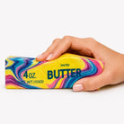 a 4oz butter-stick inspired squishy with a marbled design, salted butter label, soft squeezable texture, and clear individual packaging in cotton candy swirl (pink)