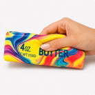 a 4oz butter-stick inspired squishy with a marbled design, salted butter label, soft squeezable texture, and clear individual packaging in rainbow swirl (red)