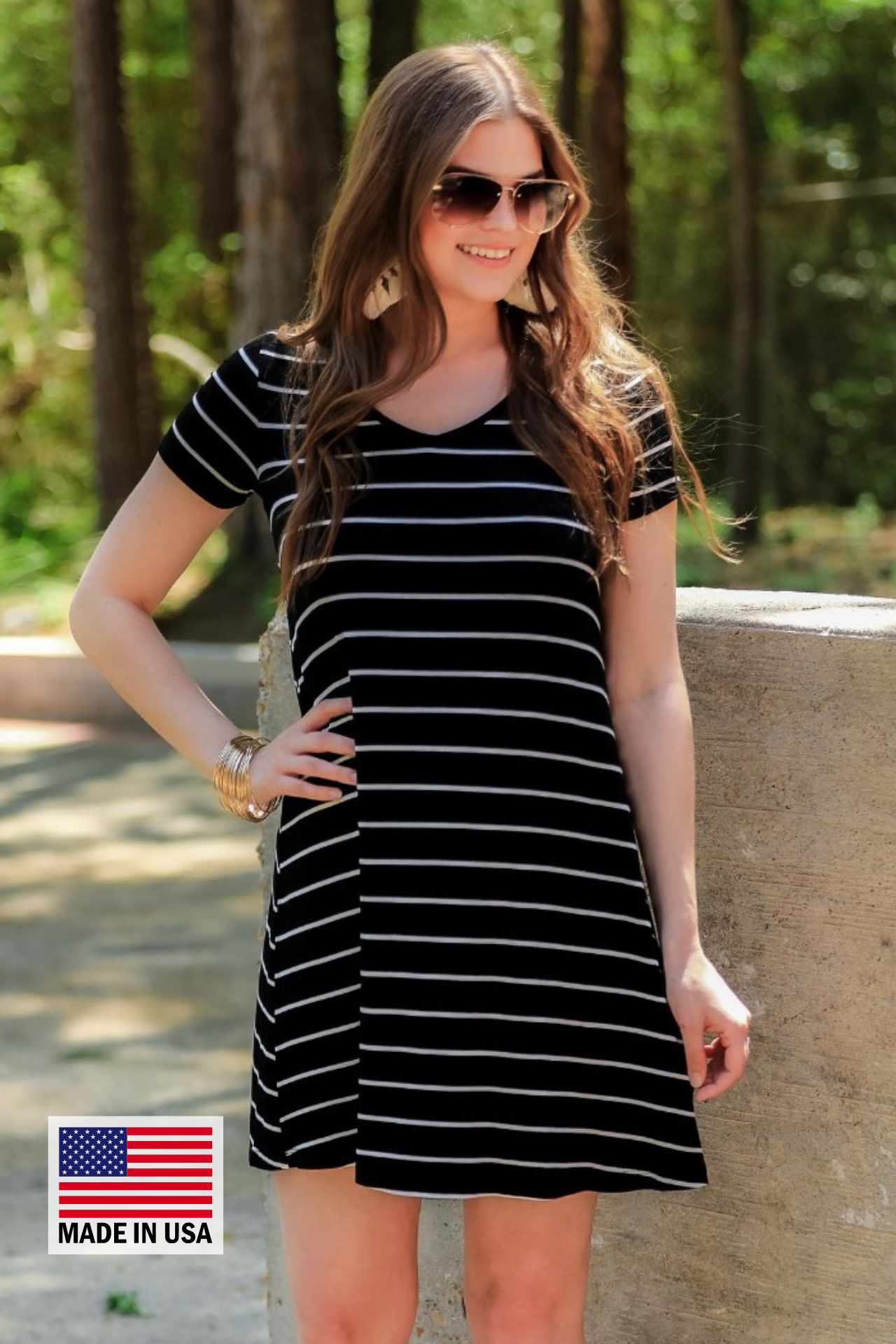 a soft stretchy knit dress with a V-neckline, short sleeves, a relaxed A-line silhouette, a straight hemline, and a horizontal white stripe pattern on a solid black background with a MADE IN USA watermark in the bottom left hand corner