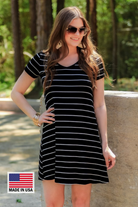 a soft stretchy knit dress with a V-neckline, short sleeves, a relaxed A-line silhouette, a straight hemline, and a horizontal white stripe pattern on a solid black background with a MADE IN USA watermark in the bottom left hand corner