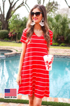 a soft stretchy knit dress with a V-neckline, short sleeves, a relaxed A-line silhouette, a straight hemline, and a horizontal white stripe pattern on a solid red background with a MADE IN USA watermark in the bottom left hand corner