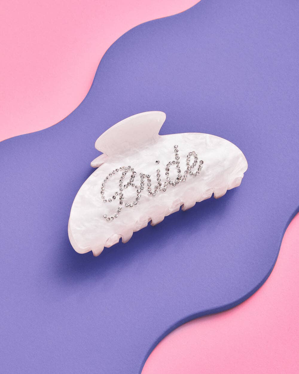 White hair clip with 'Bride' embellishments on a pink and purple background