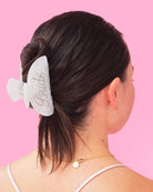 Woman with a white hair scrunchie in her hair against a pink background