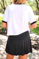a black pleated tennis skort with built-in shorts, wide comfort waistband, 4-way stretch, and moisture-wicking polyester/spandex blend fabric