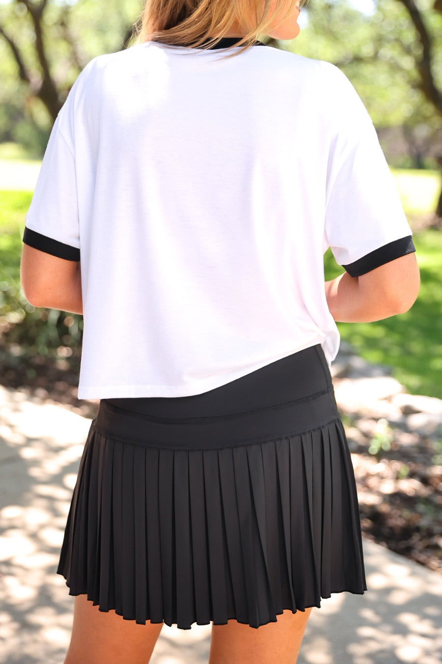 a black pleated tennis skort with built-in shorts, wide comfort waistband, 4-way stretch, and moisture-wicking polyester/spandex blend fabric