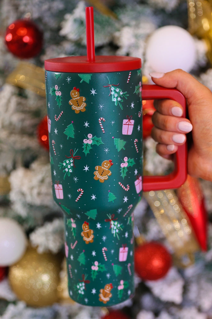 40-ounce tumbler with an exclusively designed pattern of candy canes, Christmas trees, gifts, gingerbread girls, mistletoes, snow, and stars on an emerald green background, handle, screw-on lid, and reusable straw