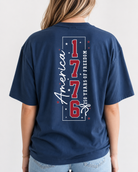 a soft navy unisex Gildan t-shirt with a crew neckline, short sleeves, a front America 250 chest graphic, a bold 1776 America back design, a 250 Years of Freedom detail, and an easy year-round fit
