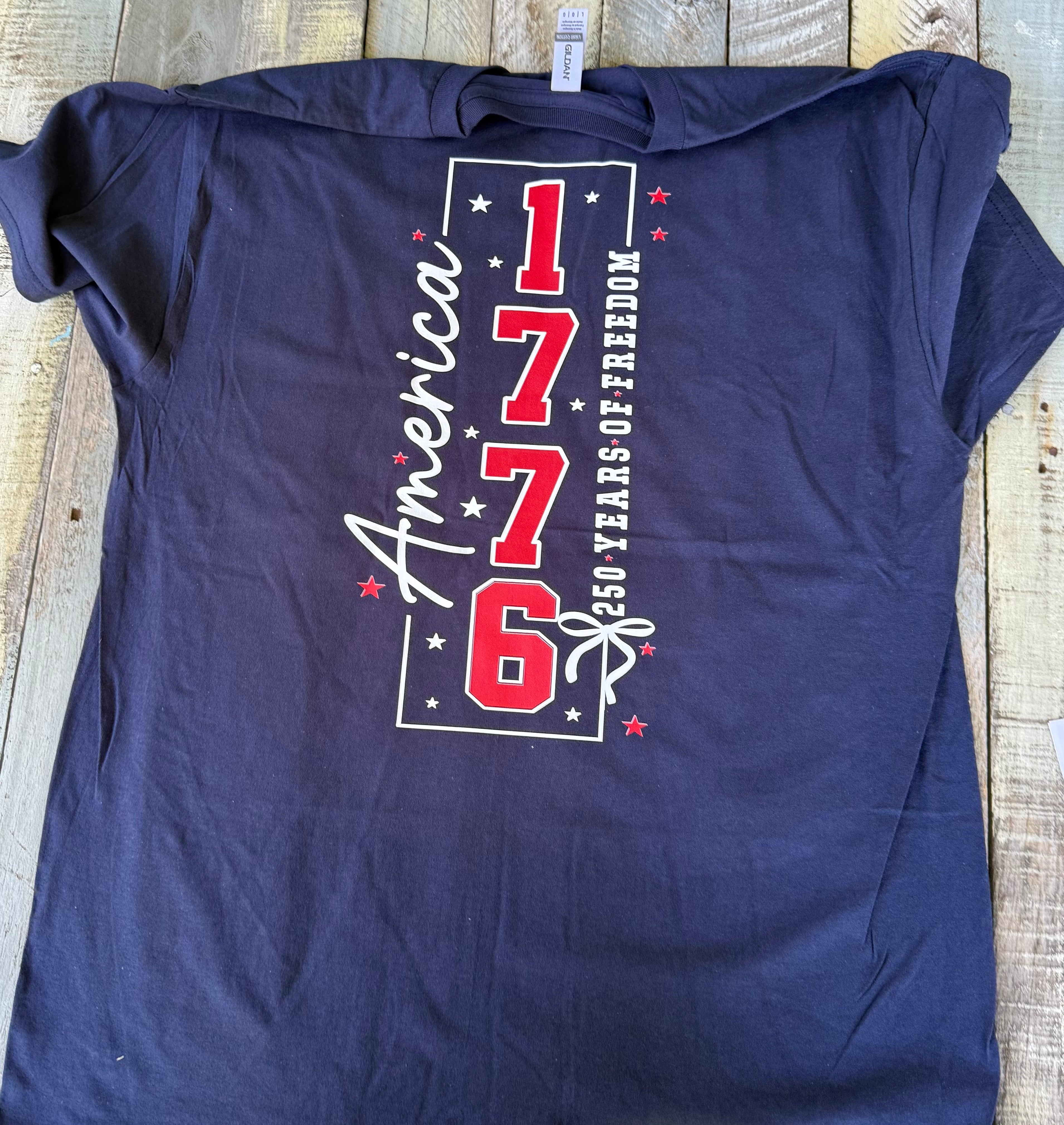 a soft navy unisex Gildan t-shirt with a crew neckline, short sleeves, a front America 250 chest graphic, a bold 1776 America back design, a 250 Years of Freedom detail, and an easy year-round fit
