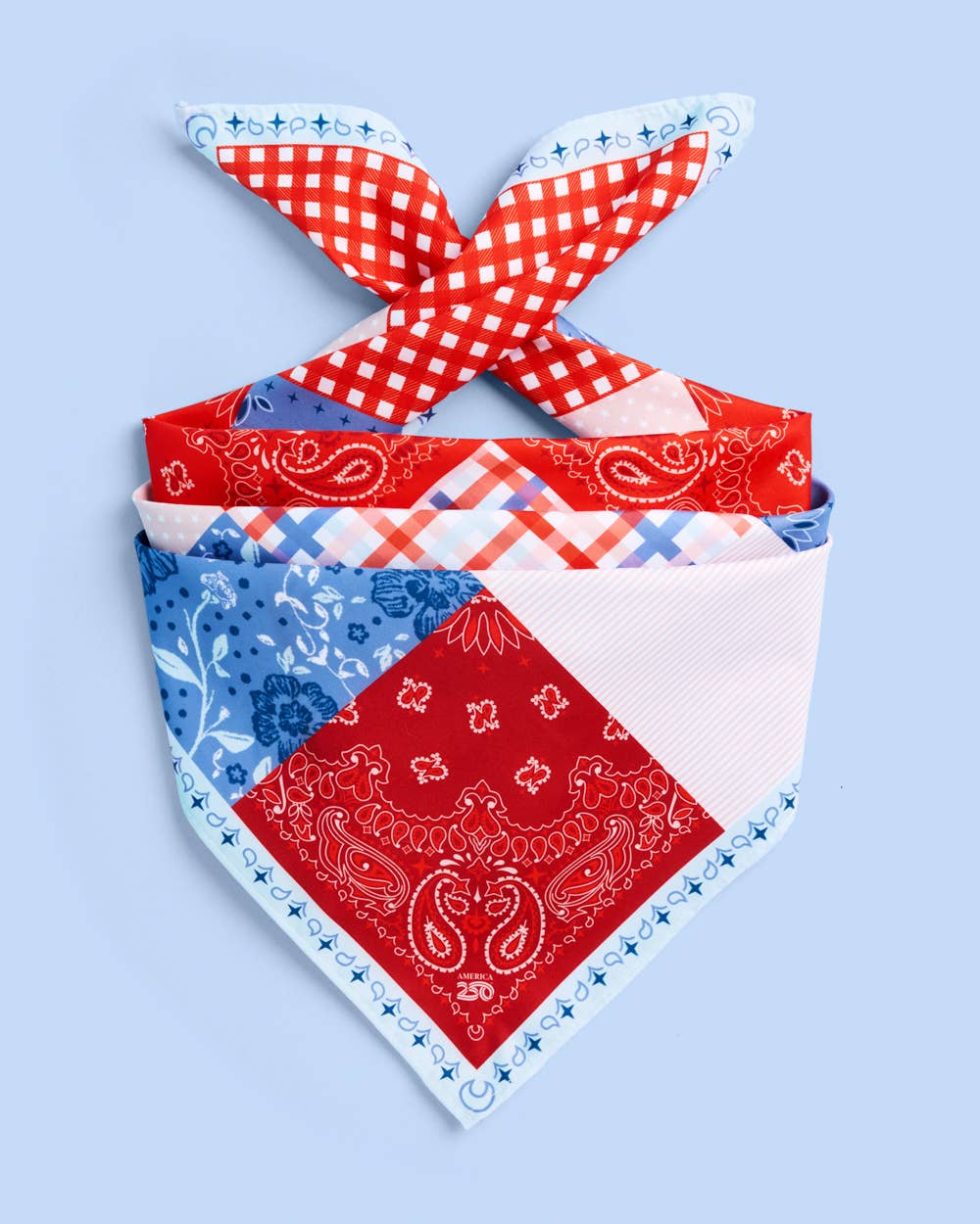 a soft silky polyester scarf with a red, white, and blue quilt-inspired print, finished with a blend of floral, gingham, and paisley details