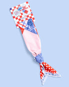 a soft silky polyester scarf with a red, white, and blue quilt-inspired print, finished with a blend of floral, gingham, and paisley details