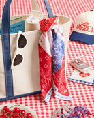 a soft silky polyester scarf with a red, white, and blue quilt-inspired print, finished with a blend of floral, gingham, and paisley details