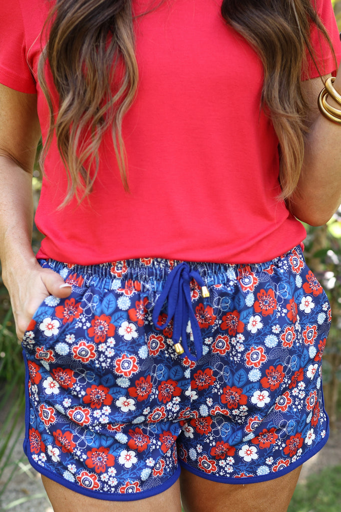 mid-rise, tie waist drawstring with gold bead accent, side pockets, &amp; relaxed fit on a red, white, &amp; blue floral print with blue piping