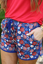 mid-rise, tie waist drawstring with gold bead accent, side pockets, &amp; relaxed fit on a red, white, &amp; blue floral print with blue piping