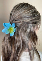 Person with blue flower hair accessory against a neutral background
