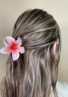 Person with blush flower hair accessory against a neutral background