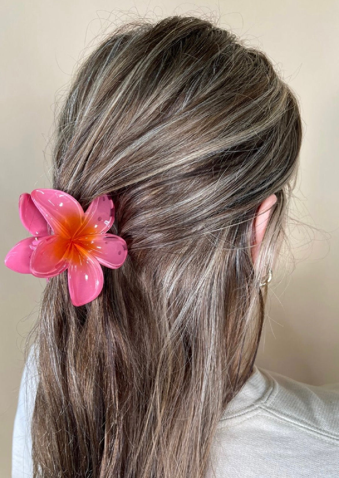 Person with coral flower hair accessory against a neutral background