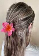 Person with coral flower hair accessory against a neutral background