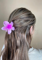 Person with pink flower hair accessory against a neutral background