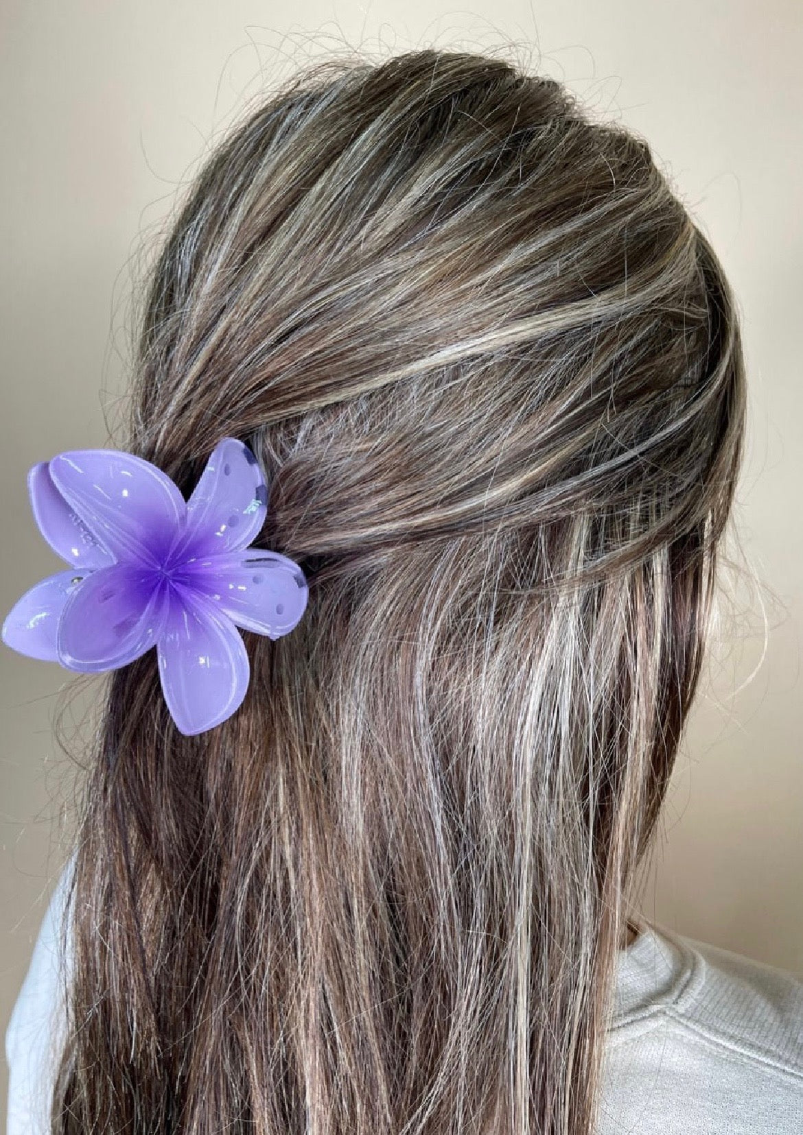 Person with purple flower hair accessory against a neutral background