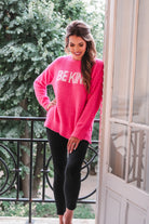 pink long-sleeve sweater made of blanket material with the wording "BE KIND" written in white