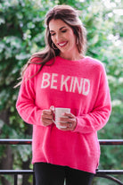 pink long-sleeve sweater made of blanket material with the wording "BE KIND" written in white