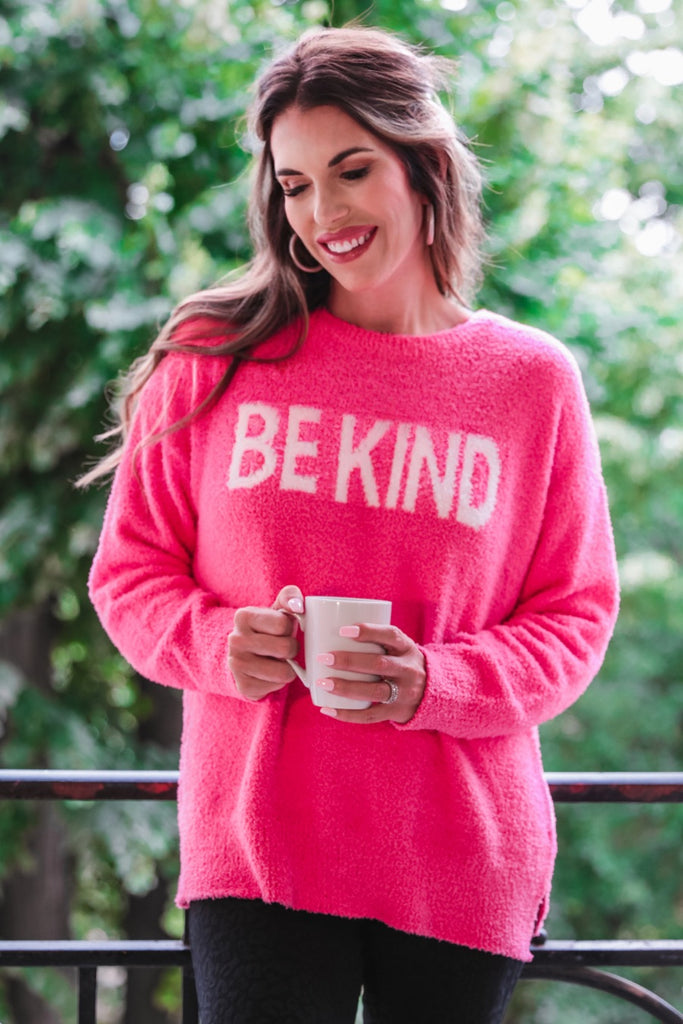 pink sweater made of blanket material with long sleeves & "BE KIND" wording in white