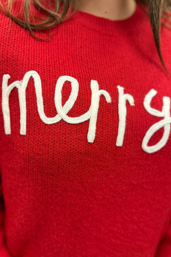 red long sleeve patterned sweater adorned with "merry" in white knit
