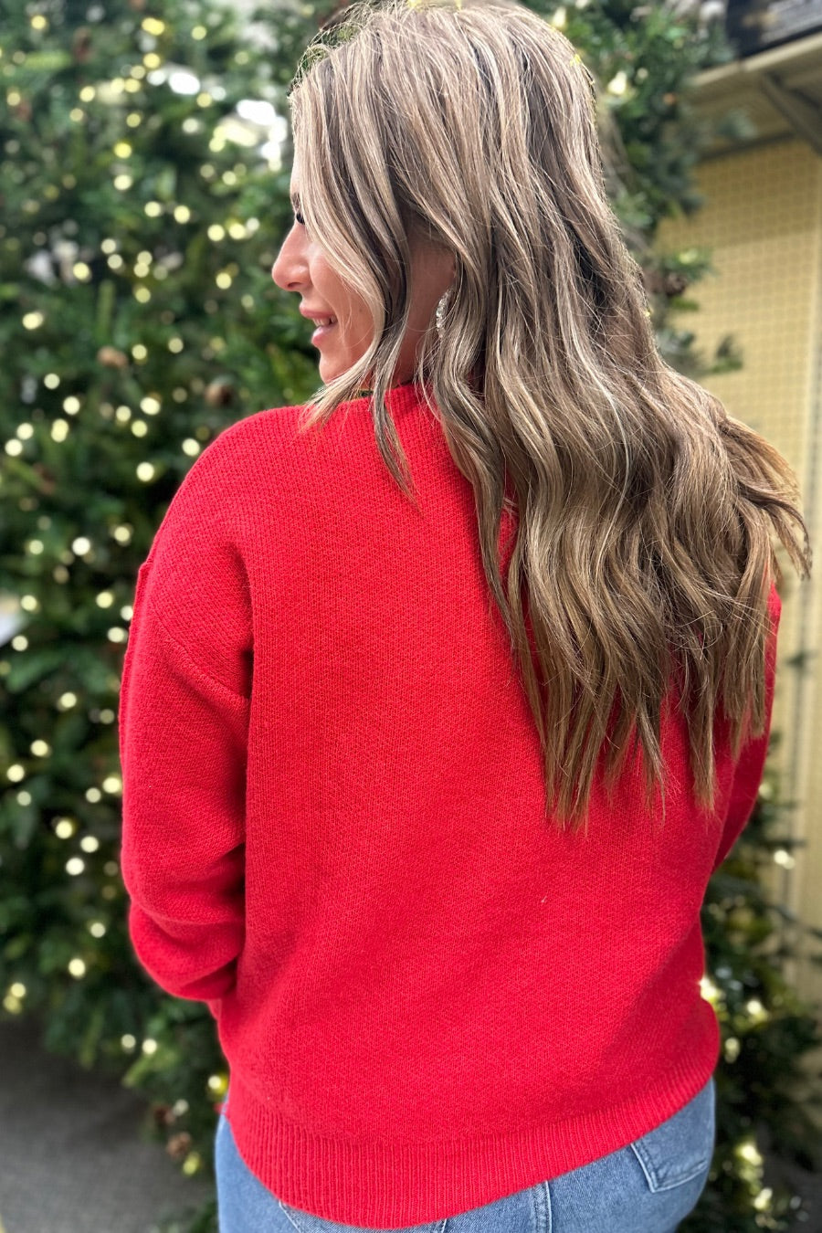 a red long-sleeve patterned sweater adorned with 'merry' script across the chest in white and ribbed detailing at the cuffs, neckline, and hem