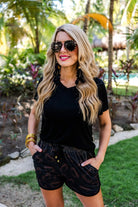 mid-rise relaxed fit activewear shorts with side pockets and a tie waist drawstring with gold bead accents, designed on an all-over football outline pattern print fabric, black base, and black trim