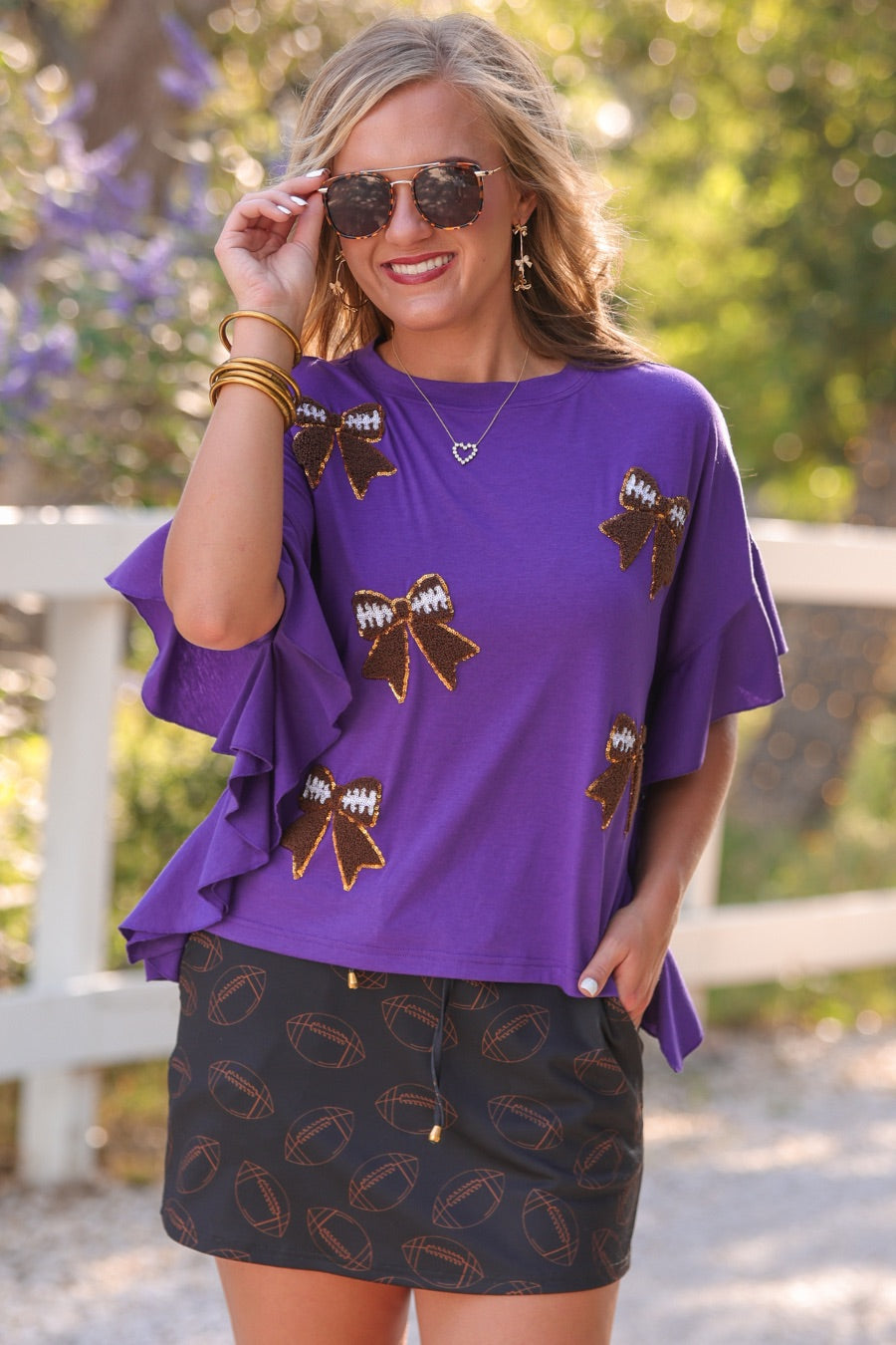 mid-rise relaxed fit everyday skort made of lightweight material with built-in cream shorts, drawstring tie with gold bead accents, an elastic band on the back, and side pockets, designed on an all-over football outline pattern print fabric in black