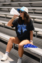 a black Comfort Colors tee crafted on soft garment-dyed cotton with a DTF-printed blue faux glitter football bow graphic, crew neckline, and short sleeves in both youth and adult sizing