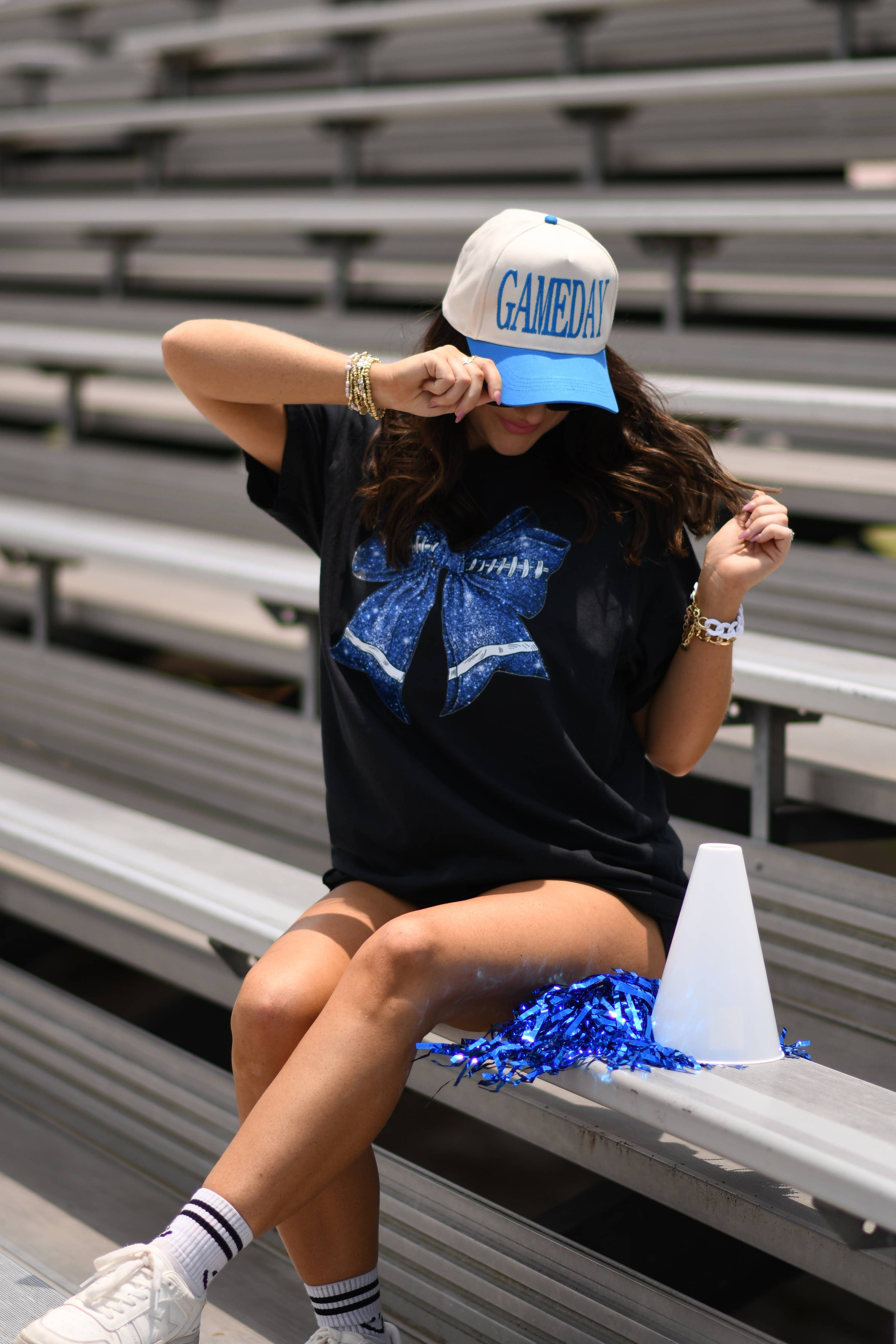 a black Comfort Colors tee crafted on soft garment-dyed cotton with a DTF-printed blue faux glitter football bow graphic, crew neckline, and short sleeves in both youth and adult sizing
