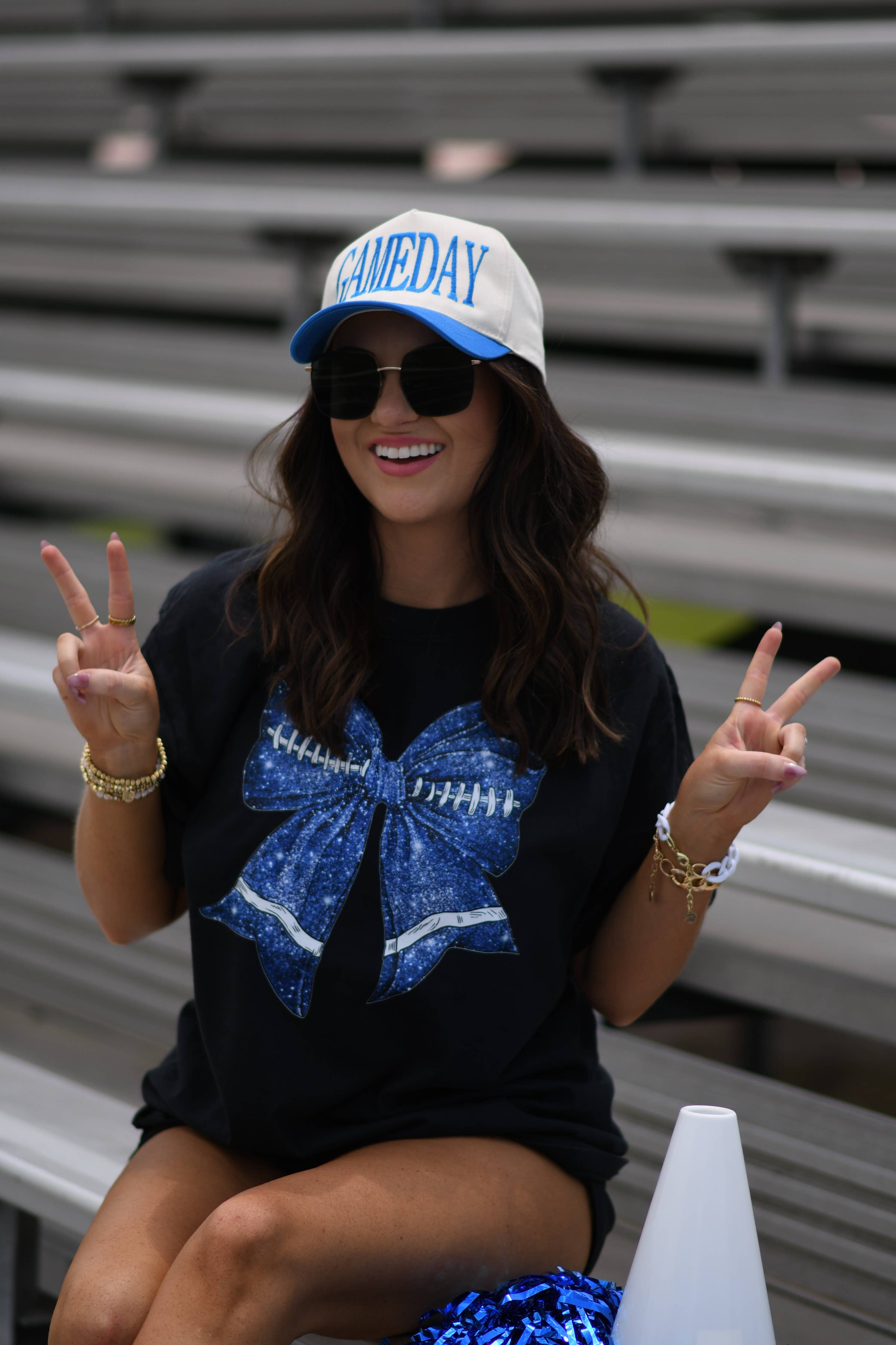 a black Comfort Colors tee crafted on soft garment-dyed cotton with a DTF-printed blue faux glitter football bow graphic, crew neckline, and short sleeves in both youth and adult sizing