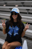 a black Comfort Colors tee crafted on soft garment-dyed cotton with a DTF-printed blue faux glitter football bow graphic, crew neckline, and short sleeves in both youth and adult sizing