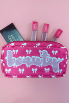 white bow pattern on a neon pink background travel bag with a zipper closure and a chenille patch bearing BEAUTY