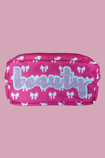 white bow pattern on a neon pink background travel bag with a zipper closure and a chenille patch bearing BEAUTY