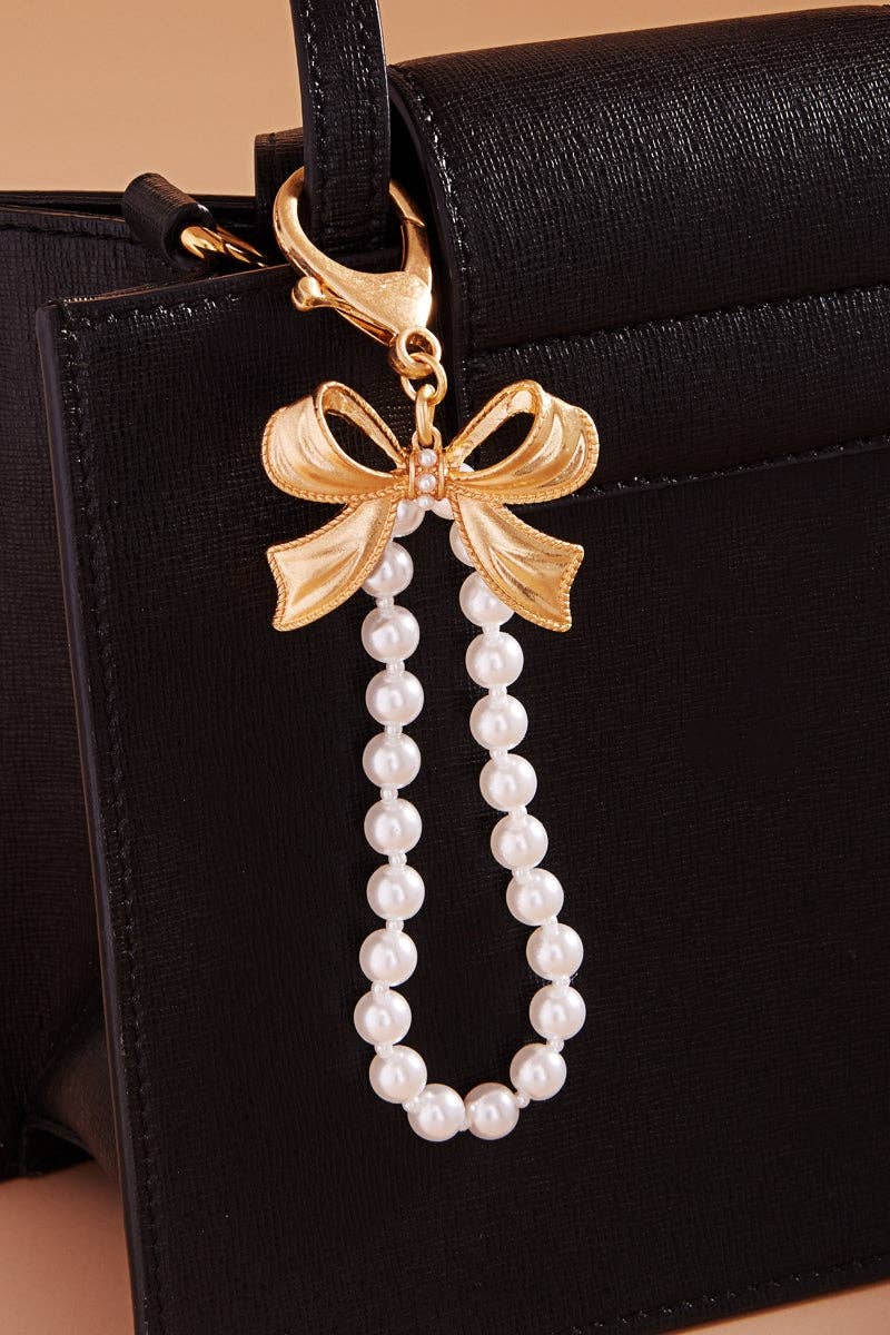 Gold bow and pearl charm on a black handbag