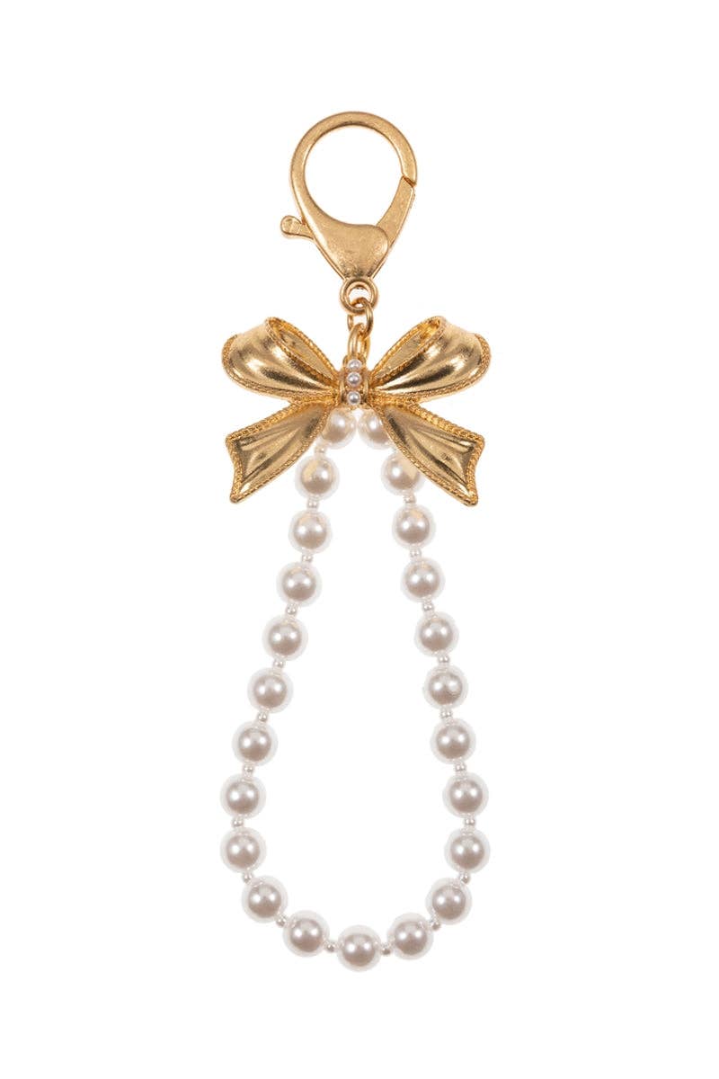 Gold bow charm with pearl necklace on a white background