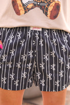 mid-rise relaxed fit boxer shorts with side pockets and an elastic waistband, designed on a bow and stripe pattern print and a solid base in black