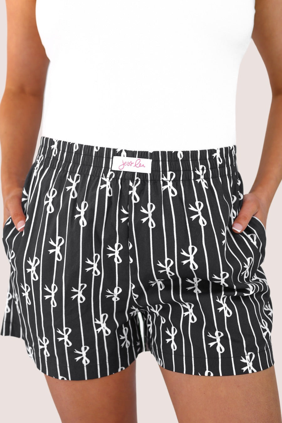 mid-rise relaxed fit boxer shorts with side pockets and an elastic waistband, designed on a bow and stripe pattern print and a solid base in black