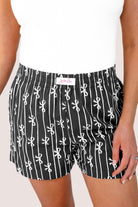 mid-rise relaxed fit boxer shorts with side pockets and an elastic waistband, designed on a bow and stripe pattern print and a solid base in black