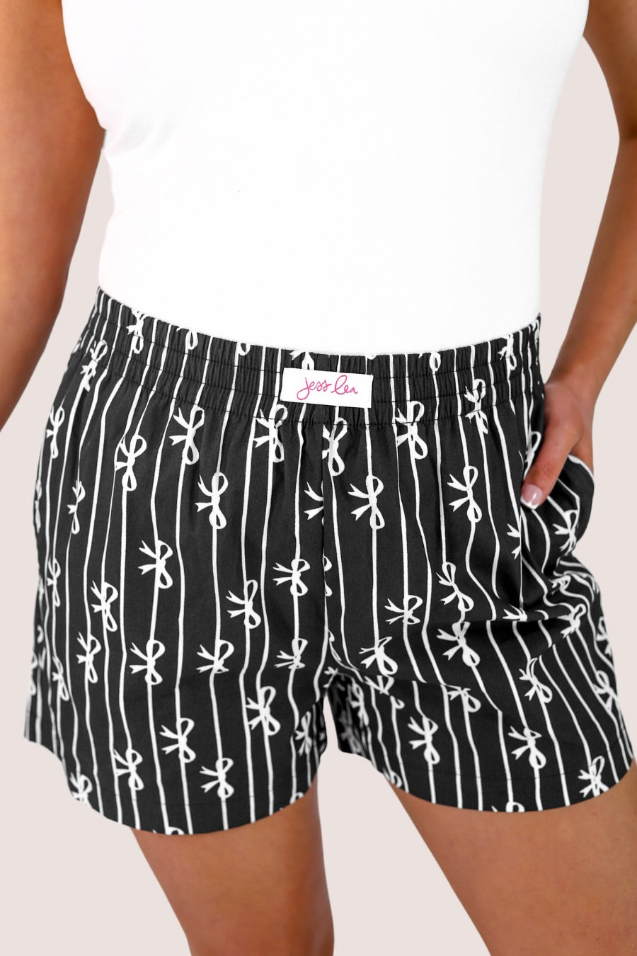 mid-rise relaxed fit boxer shorts with side pockets and an elastic waistband, designed on a bow and stripe pattern print and a solid base in black