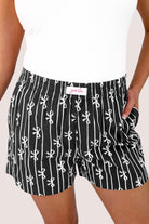 mid-rise relaxed fit boxer shorts with side pockets and an elastic waistband, designed on a bow and stripe pattern print and a solid base in black