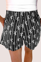 mid-rise relaxed fit boxer shorts with side pockets and an elastic waistband, designed on a bow and stripe pattern print and a solid base in black