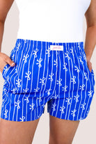 mid-rise relaxed fit boxer shorts with side pockets and an elastic waistband, designed on a bow and stripe pattern print and a solid base in blue