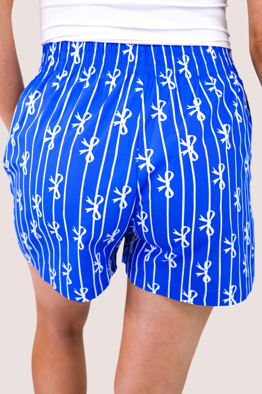 mid-rise relaxed fit boxer shorts with side pockets and an elastic waistband, designed on a bow and stripe pattern print and a solid base in blue