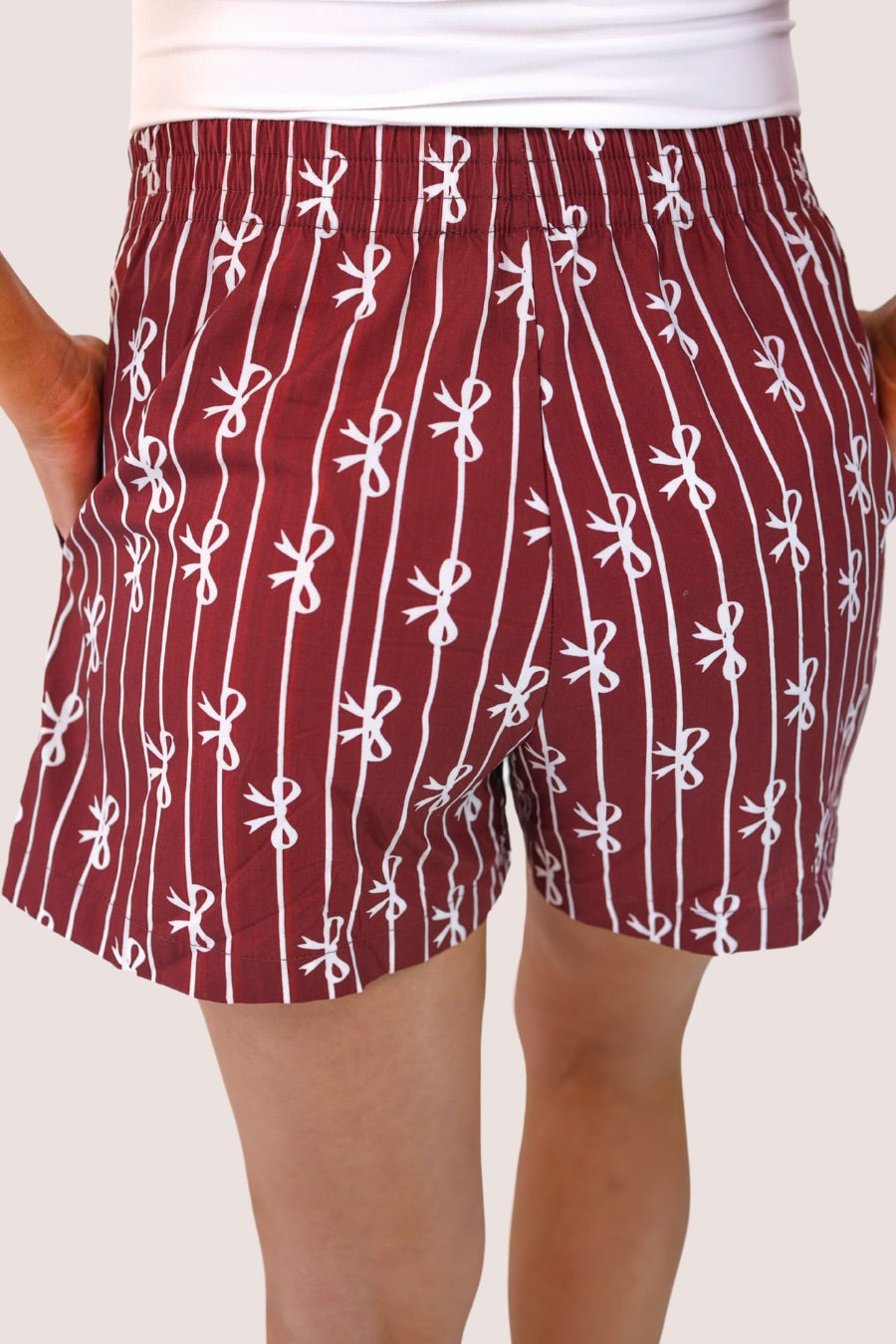 mid-rise relaxed fit boxer shorts with side pockets and an elastic waistband, designed on a bow and stripe pattern print and a solid base in maroon