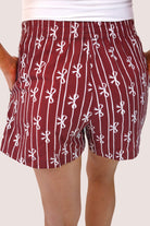 mid-rise relaxed fit boxer shorts with side pockets and an elastic waistband, designed on a bow and stripe pattern print and a solid base in maroon