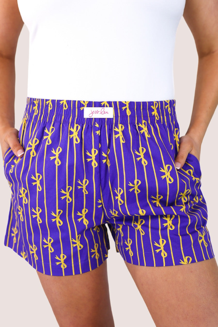 mid-rise relaxed fit boxer shorts with side pockets and an elastic waistband, designed on a bow and stripe pattern print and a solid base in purple
