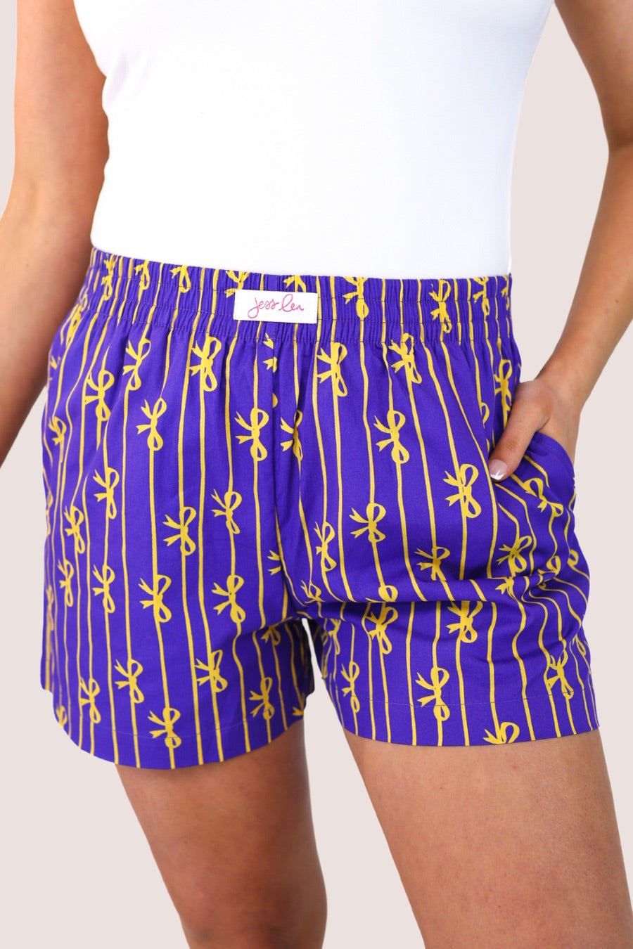 mid-rise relaxed fit boxer shorts with side pockets and an elastic waistband, designed on a bow and stripe pattern print and a solid base in purple